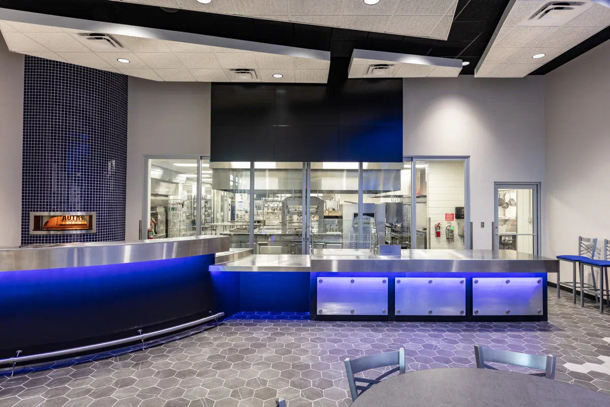 Student-run café serving counter with blue tile and illuminated millwork