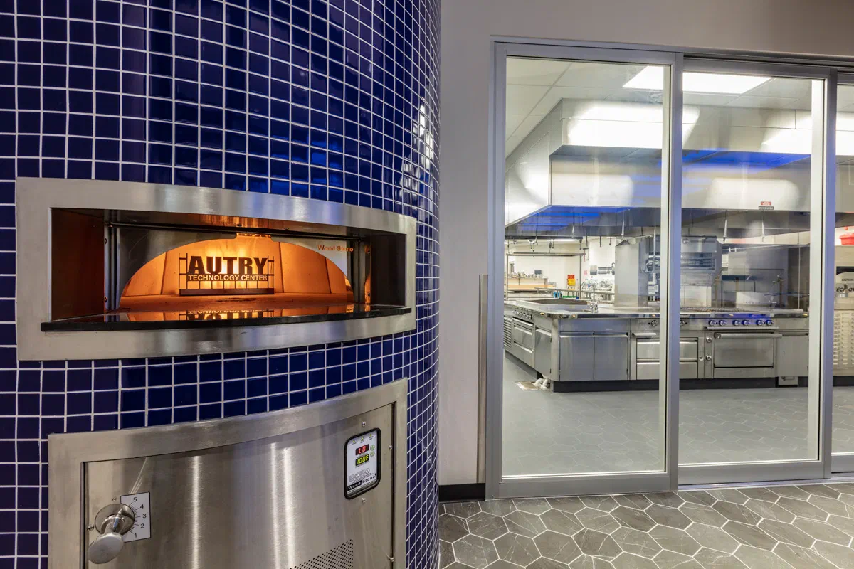 Custom wood-fired pizza oven clad in blue tile branded Autry
