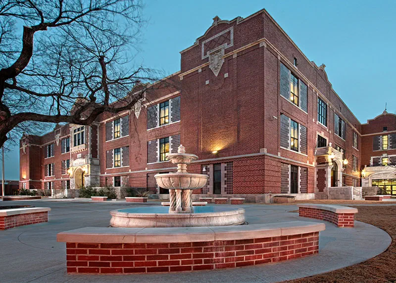 Historic Enid High School brick facade and restored fountain plaza at dusk