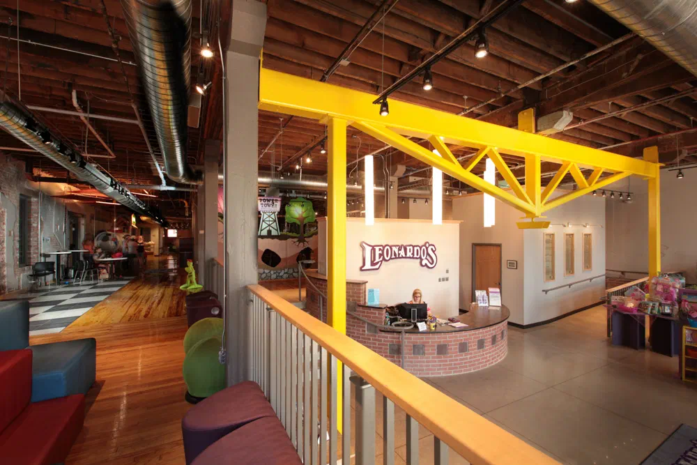 Leonardo's museum lobby with yellow steel trusses, reception desk and exposed ductwork