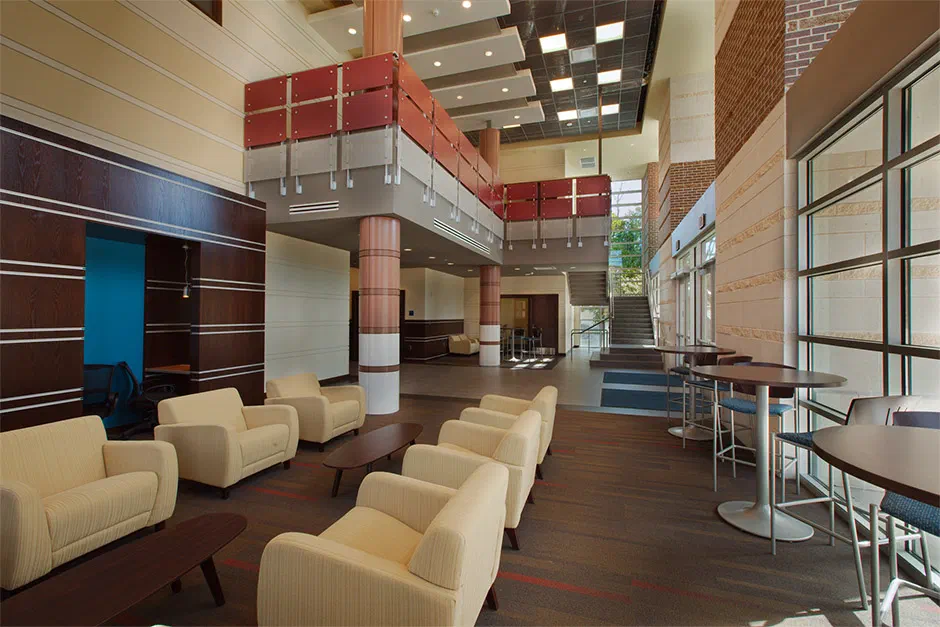 University Center lobby at Enid High School with lounge seating, wood panels and two-story glass