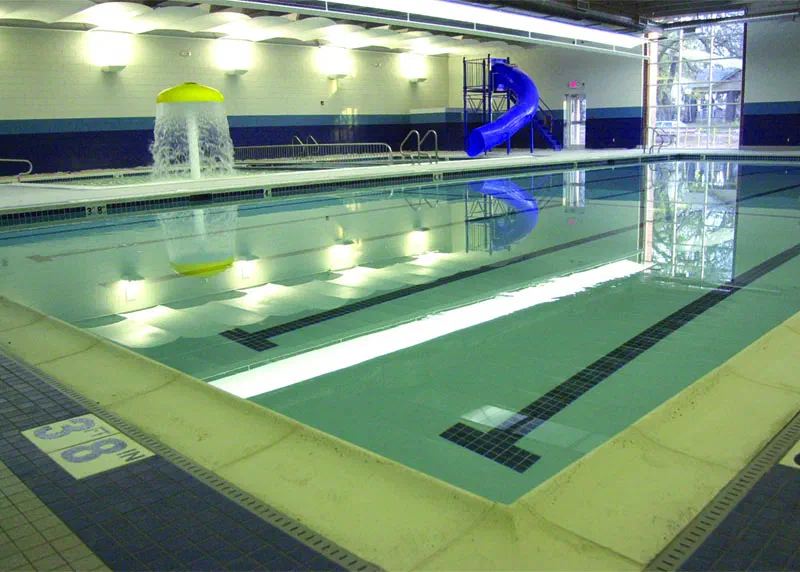 YMCA natatorium indoor pool with lap lanes, blue water slide and interactive water features